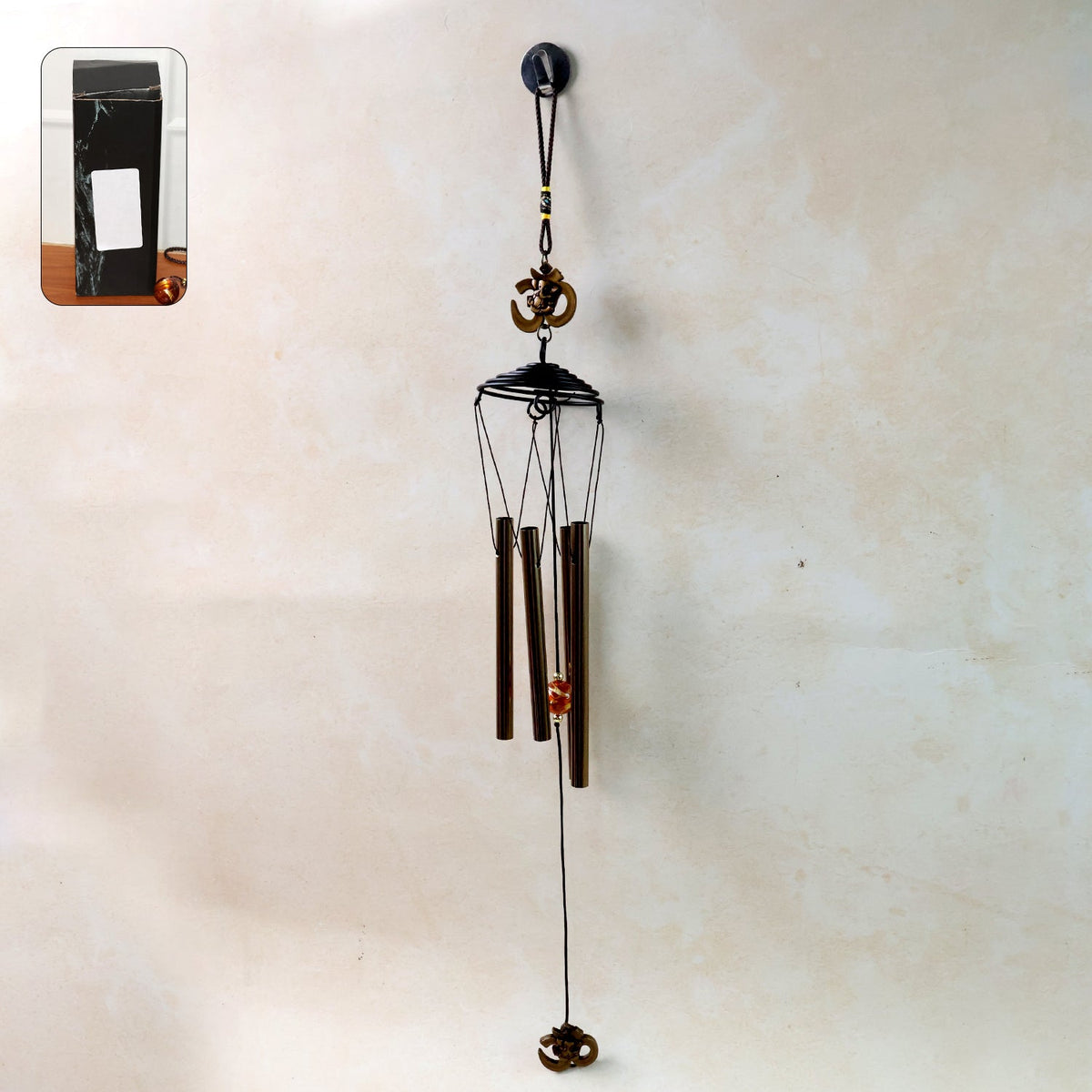 Metal wind chime with Om symbol hanging outdoors in a garden