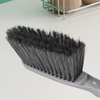 Woman using the long-handle cleaning brush for scrubbing a kitchen sink.