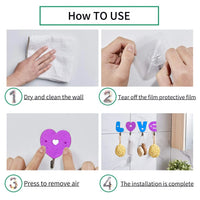 Set of three love shape self adhesive hooks on a clean white wall.