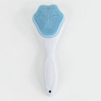 Silicone face scrubber displayed with other skincare products for a complete routine.