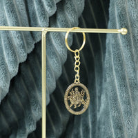 Hand holding the Maa Durga golden oval frame metal keychain