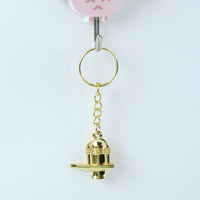 Golden Shivling metal keychain resting on a flat surface highlighting golden finish