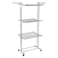 The 3-tier stainless steel drying rack with wheels, fully loaded with laundry.
