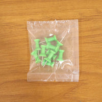 Multiple green push pins arranged showing sharp metal pins