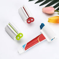 Angled view of the white rolling toothpaste squeezer with a tube, ready for daily use.
