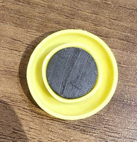 Yellow circular magnet placed next to pen for size reference