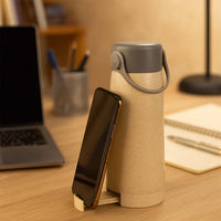 Close-up of the creative glass water bottle, highlighting the convenient phone holder feature.