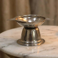 Polished metal diya stand with traditional sunflower pattern