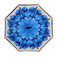 The open canopy of a reverse umbrella reveals a large, intricate blue floral design on a light background.