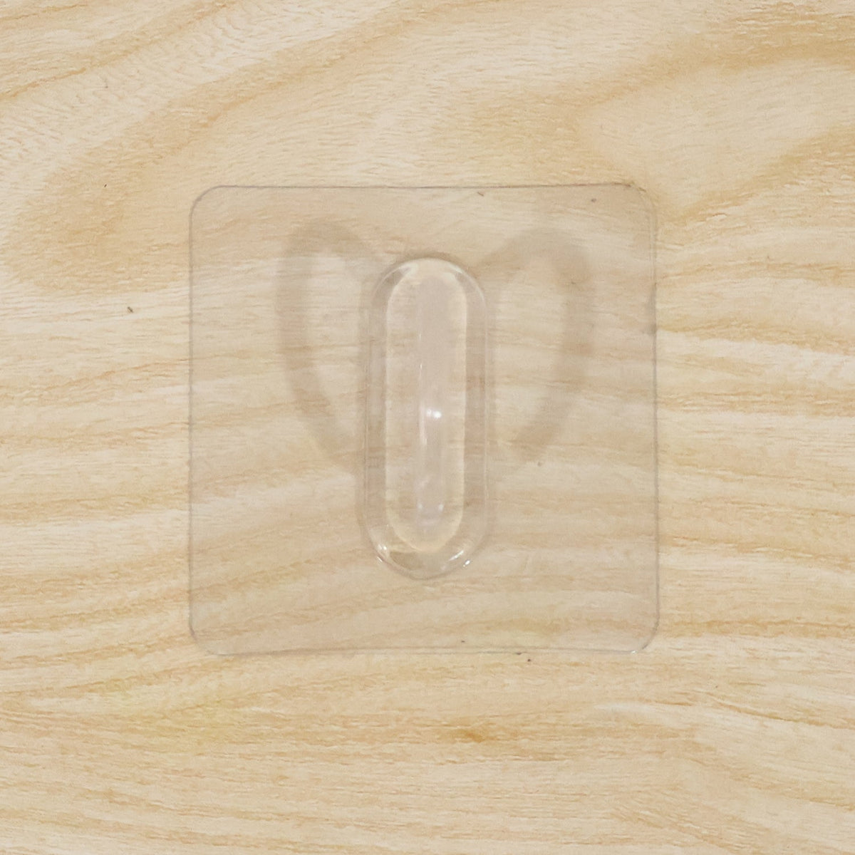 Close-up of transparent wall hook showing its adhesive pad