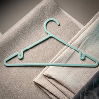 Plastic hanger holding shirt and dress, supporting heavy fabrics