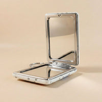 Foldable compact mirror keychain demonstrating dual-sided mirrors